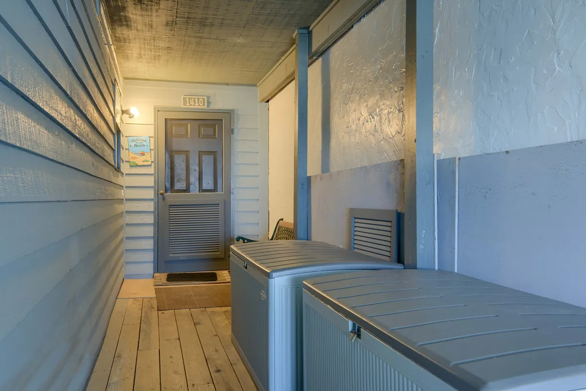 A welcoming entryway with a sturdy doorway, organized storage bins for beach equipment, and cheerful wall art. The area is designed for efficient arrivals and departures, making it easy to store or retrieve gear as needed.