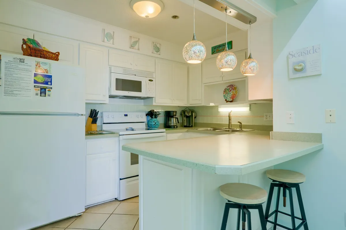 A functional and stylish kitchen with sleek countertops, modern appliances, and pendant lighting. The kitchen is open to the living and dining areas, allowing for easy socialization and meal preparation while remaining part of the group experience.