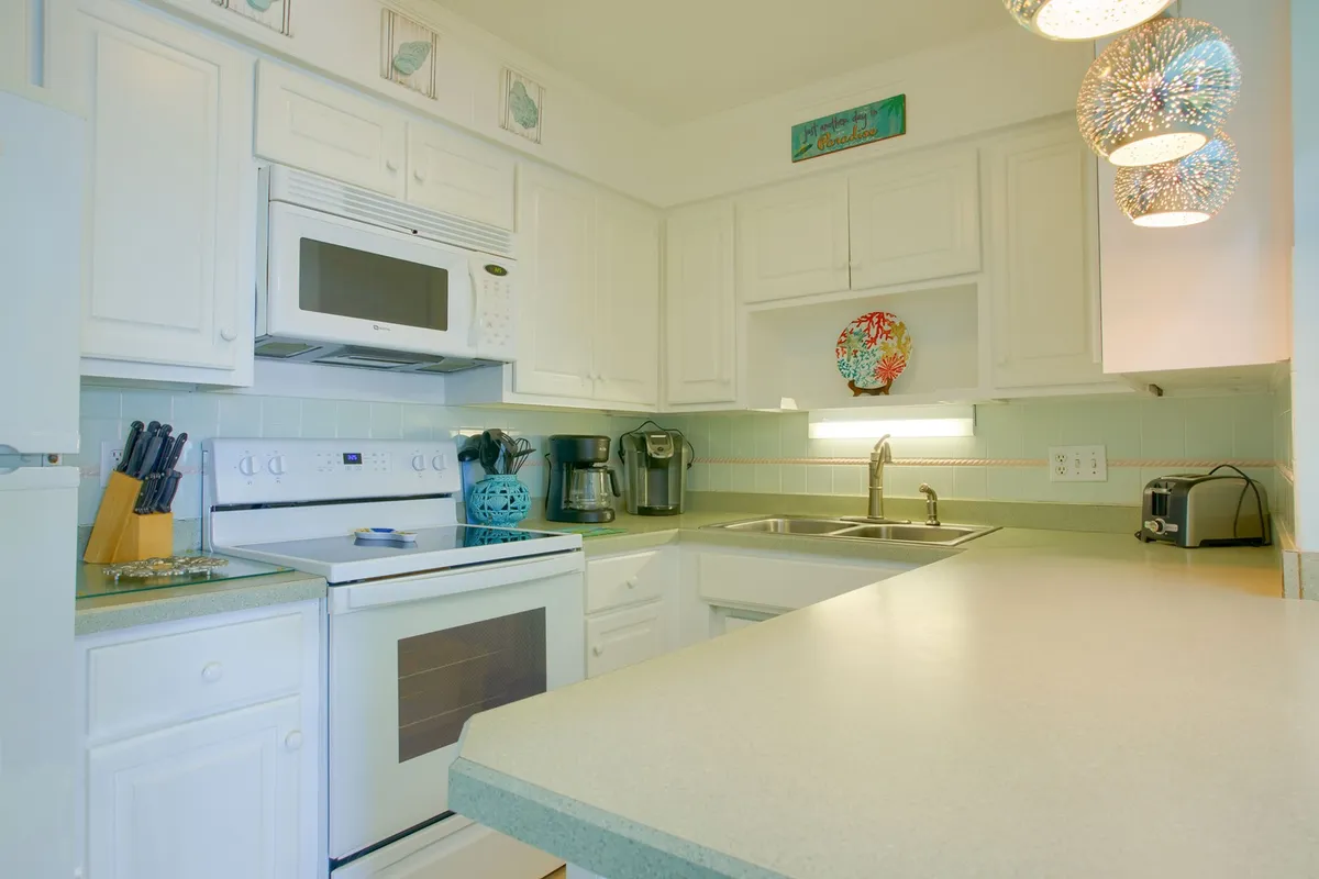 A warm and welcoming kitchen interior featuring white cabinetry, modern appliances, a stylish kitchen island, and a decorative dish. The scene evokes a sense of home, with space for cooking, entertaining, and sharing family meals.
